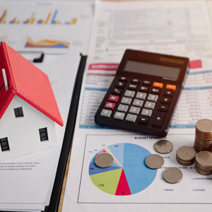 Estate tax planning concept with calculator, charts, coins, and house model on financial forms