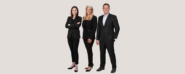 3-Attorneys-New-2 (1) Three smiling legal professionals, two women and one man, in business suits